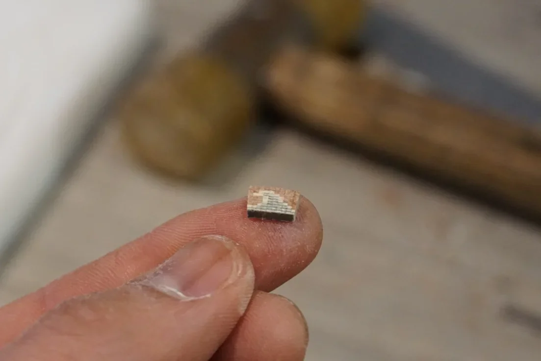 Hand holding a piece of rosette log ready to be added to a rosette.