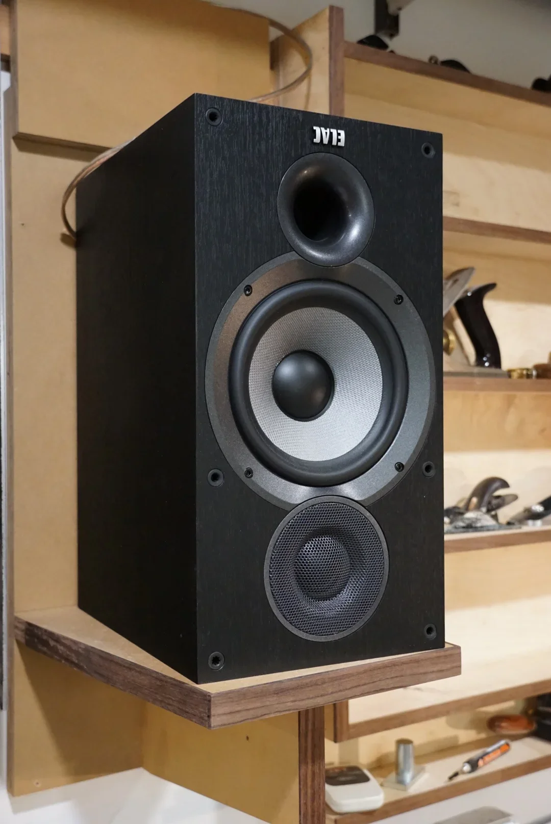 Black bookshelf speaker in a luthier shop.