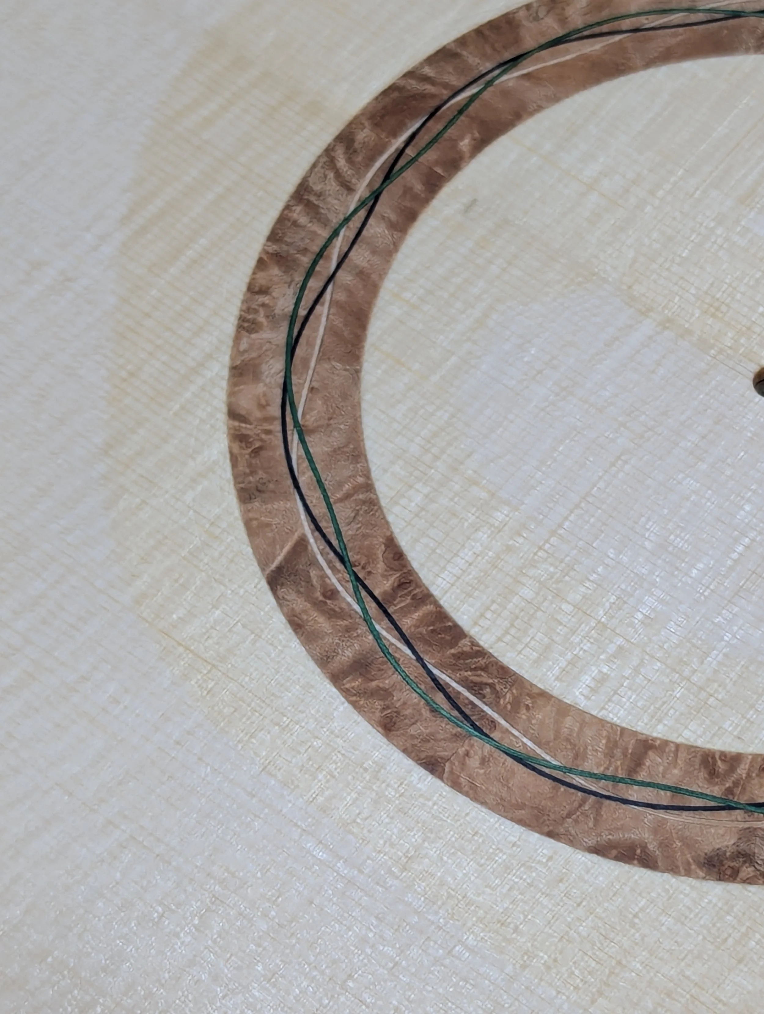 Burl rosette inlay process shot with black lines inlaid into.