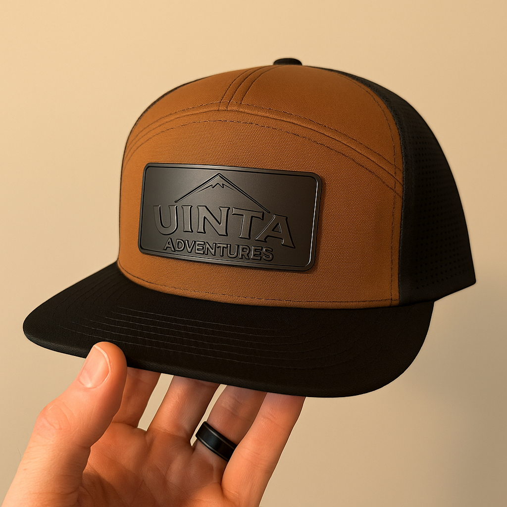A brown and black baseball cap with a rectangular logo patch that reads "Uinta Adventures".