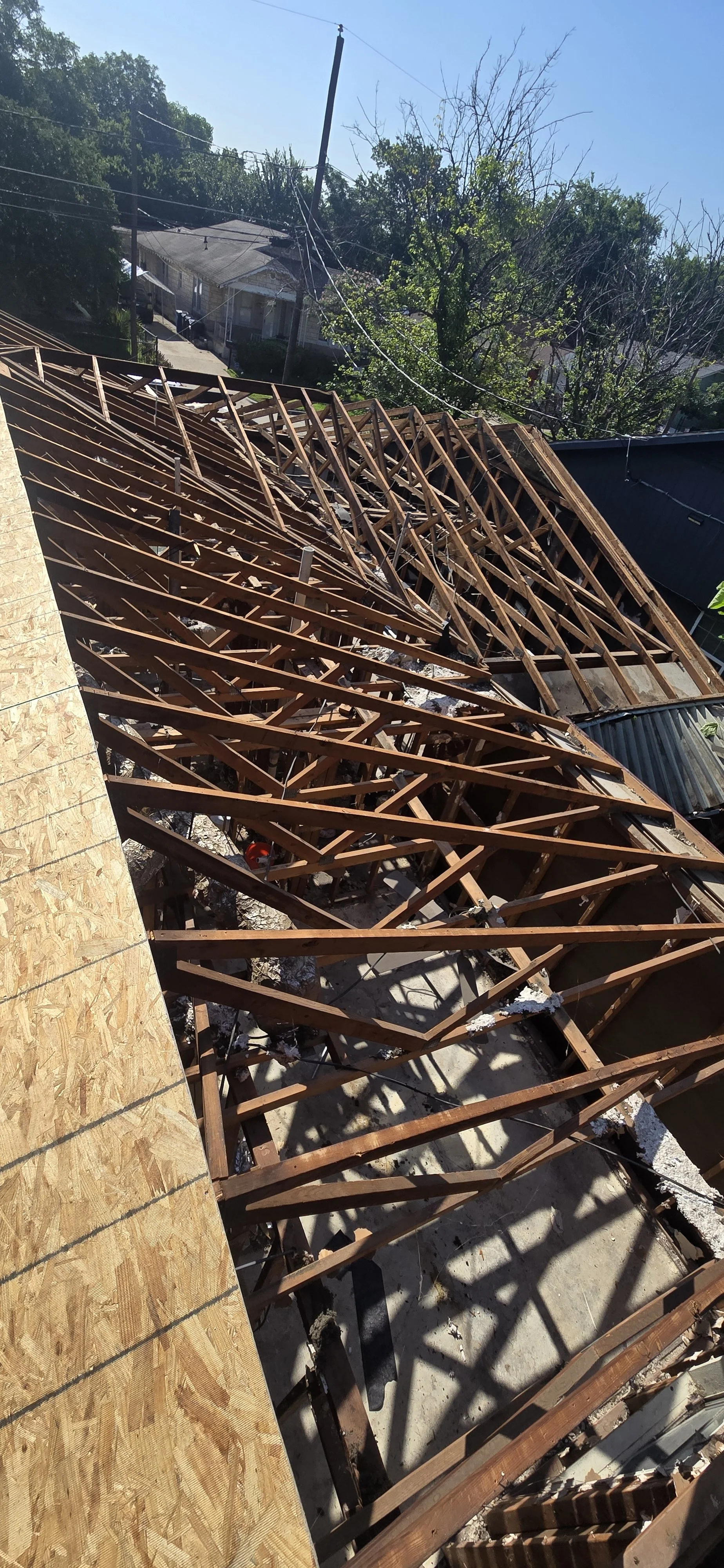 View of a house under construction with exposed wooden roof trusses.