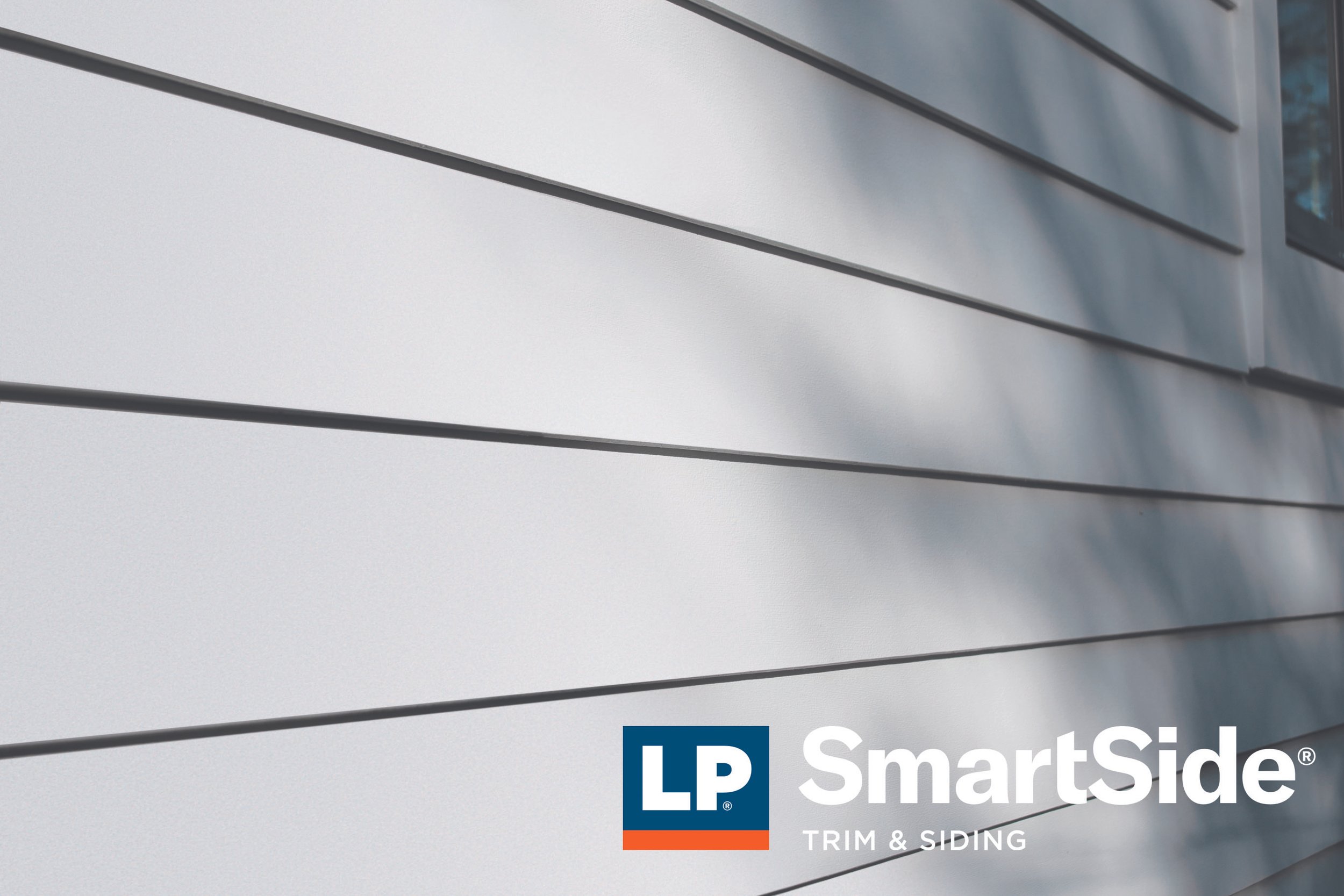 Close-up of white siding panels with LP SmartSide logo and text about trim and siding, with partial view of a building's exterior.