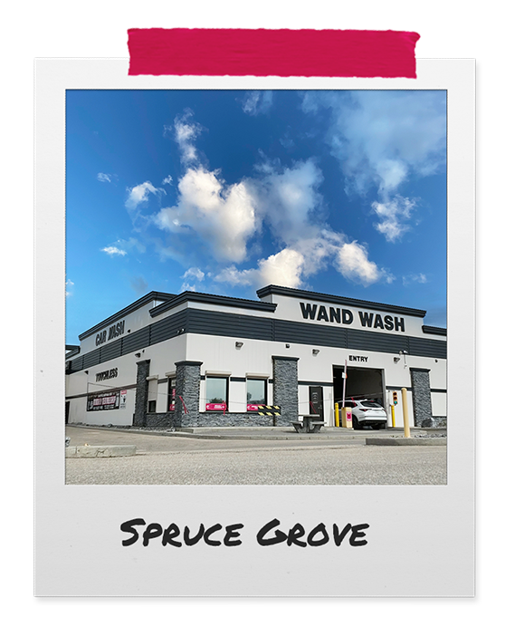 Exterior of a modern car wash building named 'Wand Wash' with a bright blue sky and clouds in the background.
