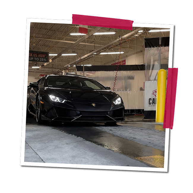 Black Lamborghini sports car inside a car wash facility.