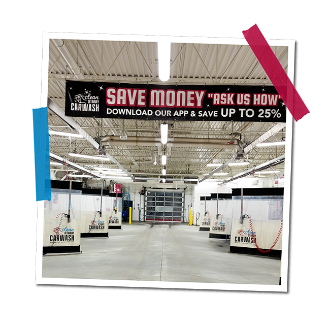 Empty indoor car wash station with multiple wash bays and a large overhead sign promoting savings and app download.
