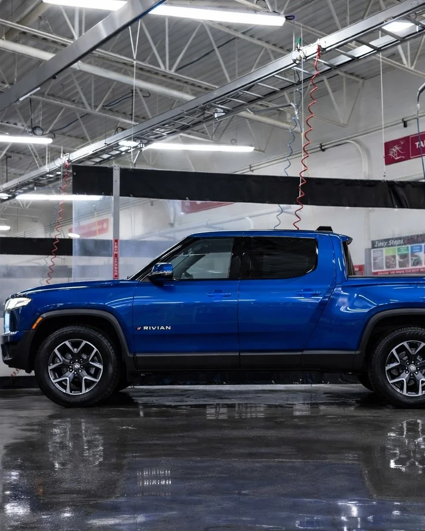 A blue Rivian electric pickup truck inside a car wash station.