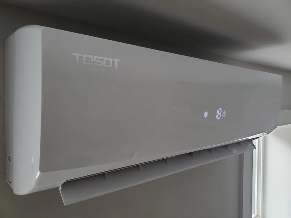 White Tosot heat pump mounted on a wall with digital display showing temperature and icons. controls heating and cooling with ducted or non ducted heatpump