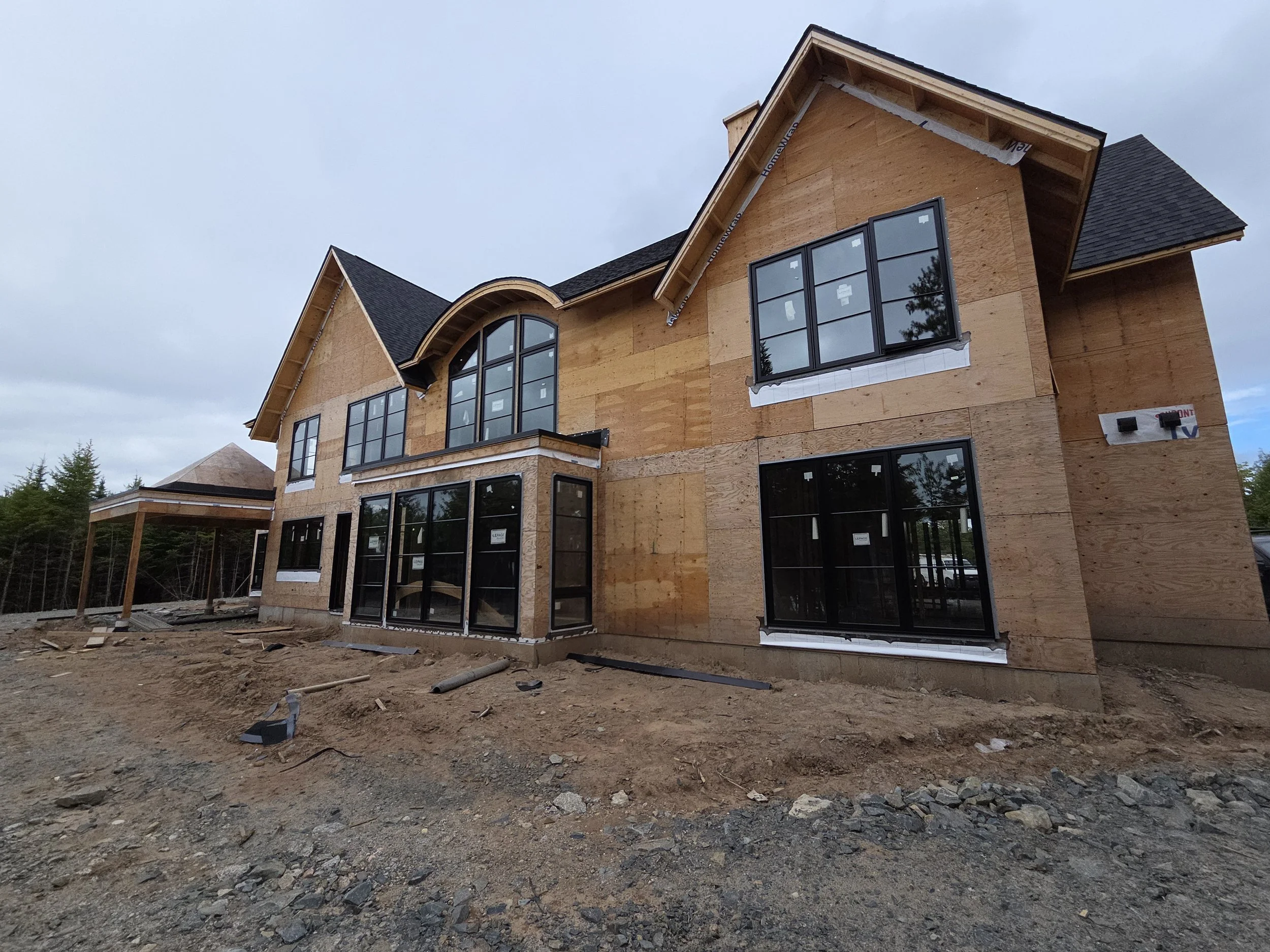 Under construction two-story house with large windows, wooden exterior sheathing, ducted heat pump, Halifax
