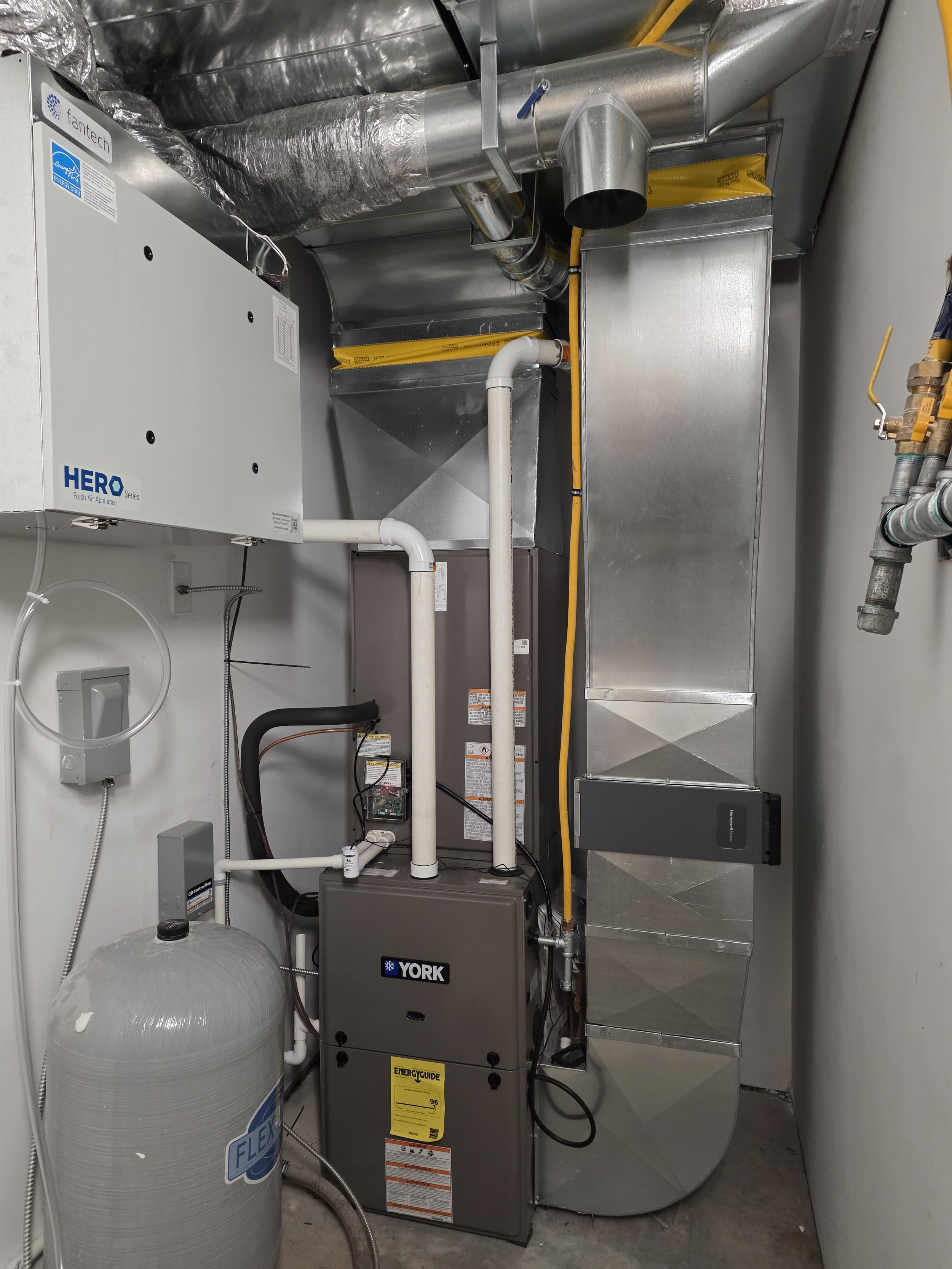 HVAC system components including a furnace, ductwork, pipes, wiring, and a water softener in a utility closet. ventilation