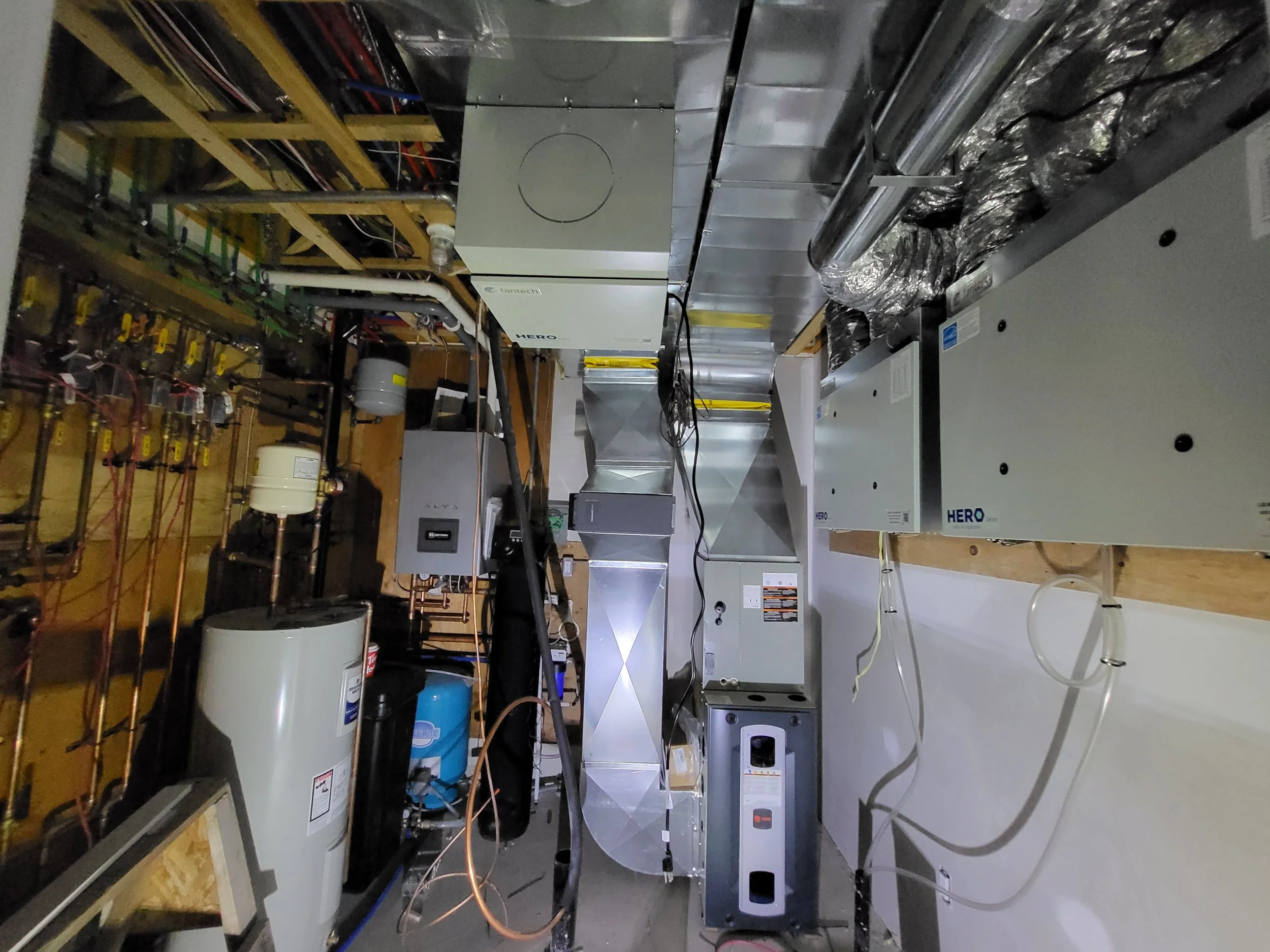 Industrial HVAC system with metal ducts, electrical panels, and plumbing, installed in a utility room. Ventilation, furnace, HRV and hepa filter