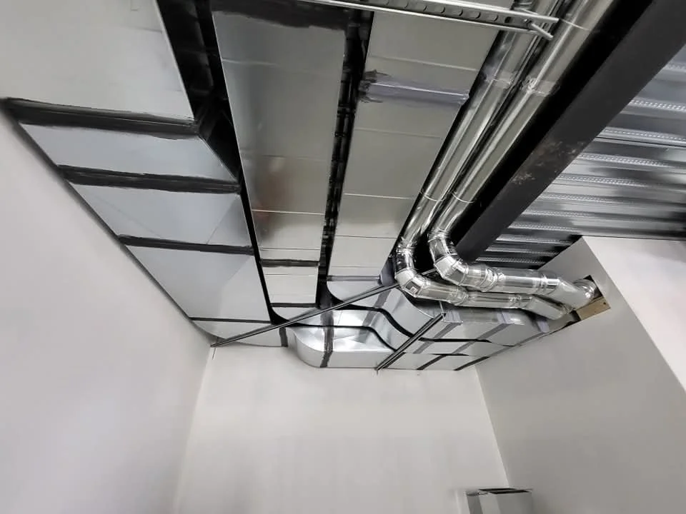 Ceiling with metallic ductwork and electrical conduits in an industrial or commercial building. 