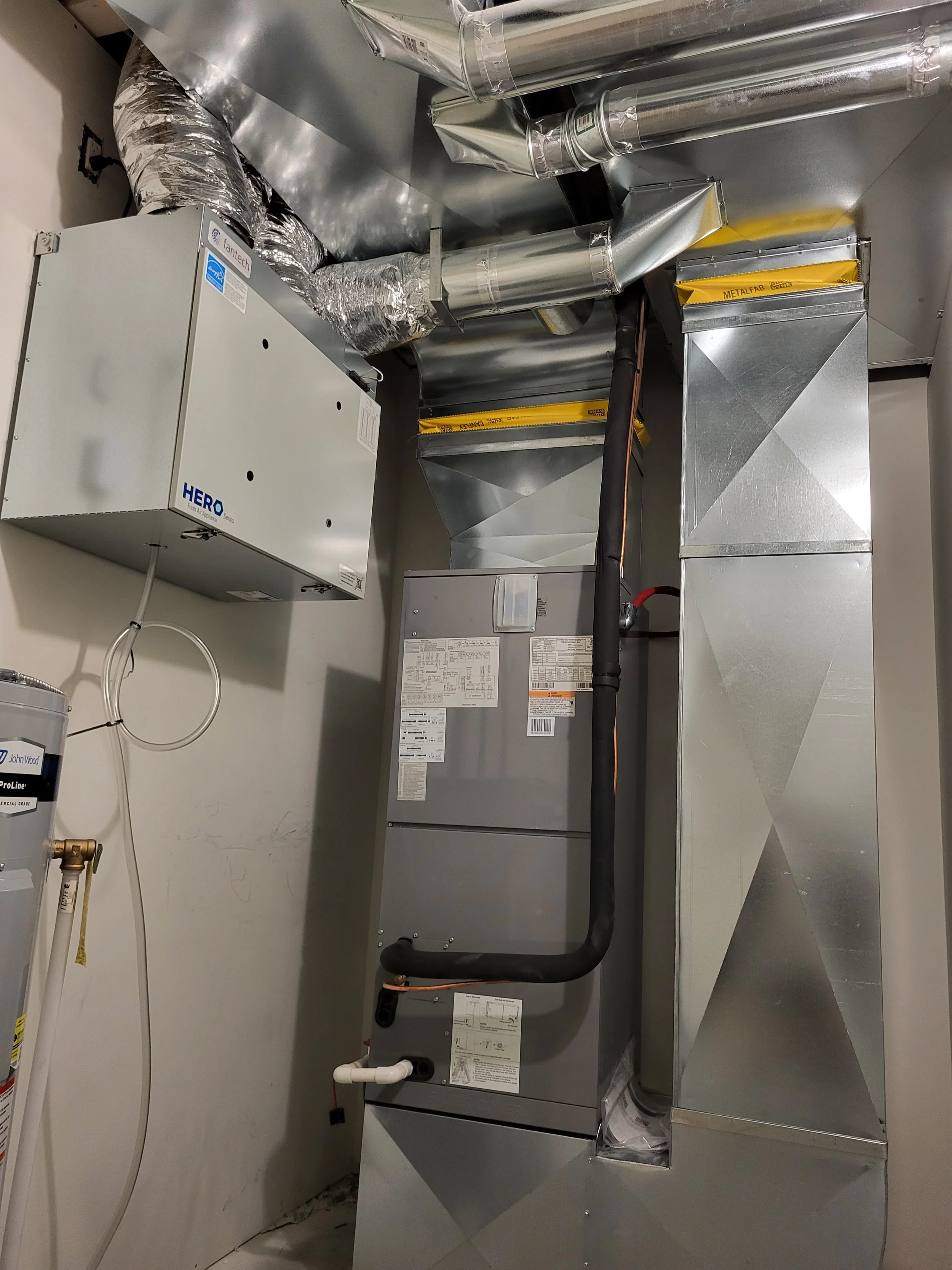 Interior of a utility closet in a residential home showing HVAC and ductwork, including a ducted heatpump, insulated ducts, and vents. HRAI certified for inspection