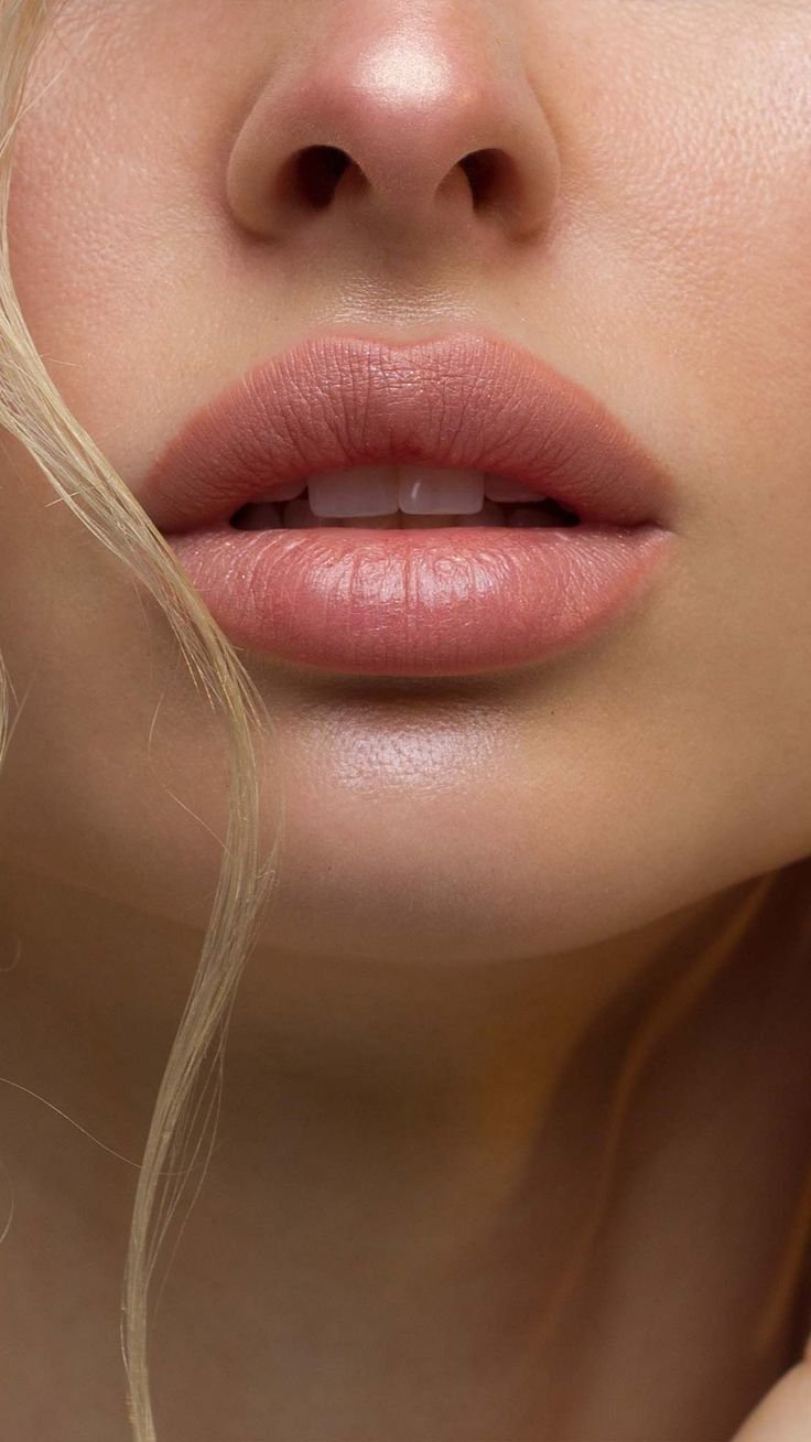 Close-up of a woman's lips slightly parted, revealing her teeth, with a portion of her nose visible above.