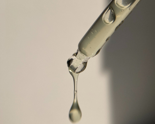 A close-up of a dropper releasing a clear liquid.