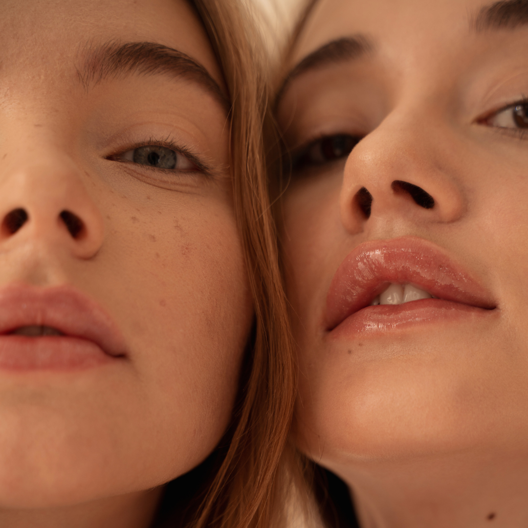 Close-up of two women with their faces close together, showing detailed facial features, skin texture, and lips.