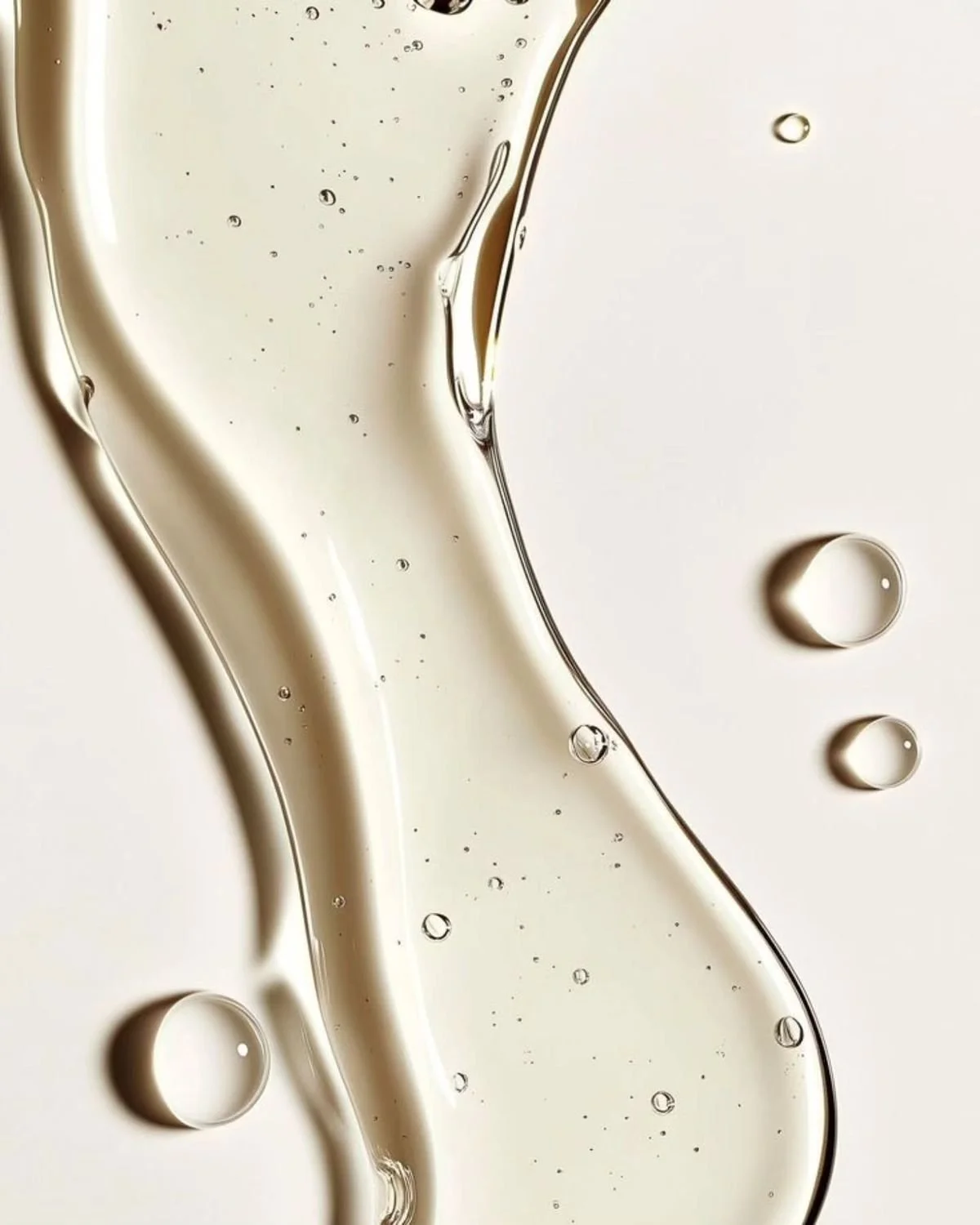 Close-up photo of a translucent serum with small bubbles and droplets, on a white background