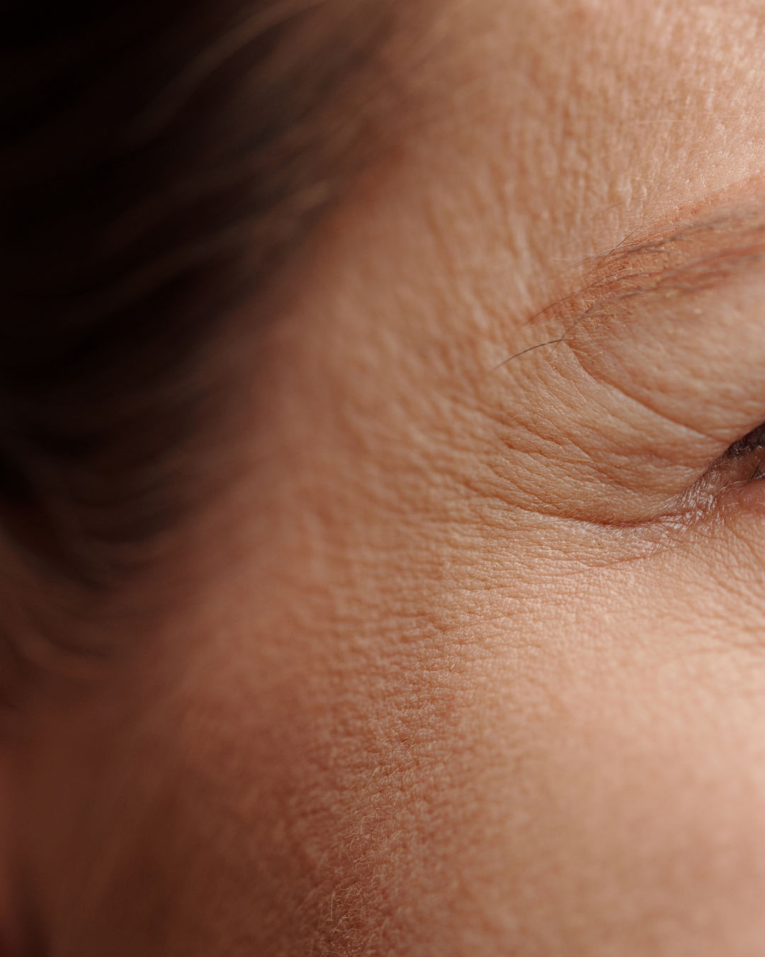 Close-up of a person's closed eye, showing detailed skin texture and eyelashes.