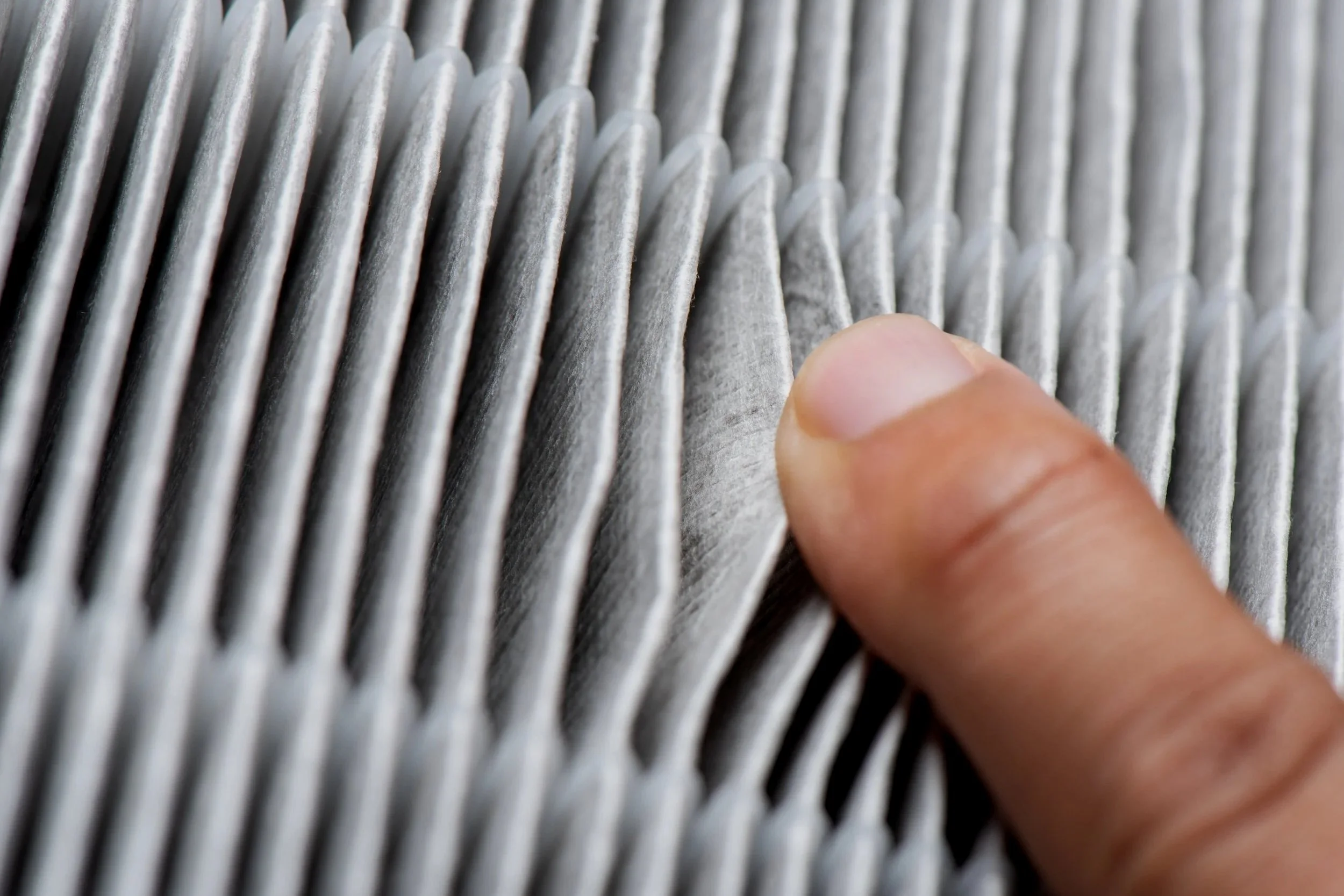 Close-up of a person's fingers touching a textured metallic surface with parallel ridges.