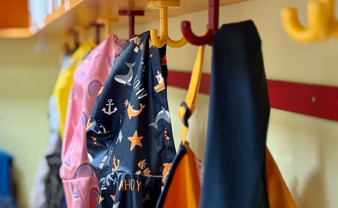 Foto Garderobe mit mehreren Kinderjacken die an bunten Haken hängen