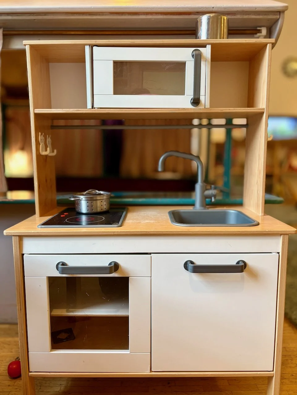 Foto von Kinderküche im Spielzimmer. Kleine Holzküche mit Herd, Spüle, Ofen und Stauraum