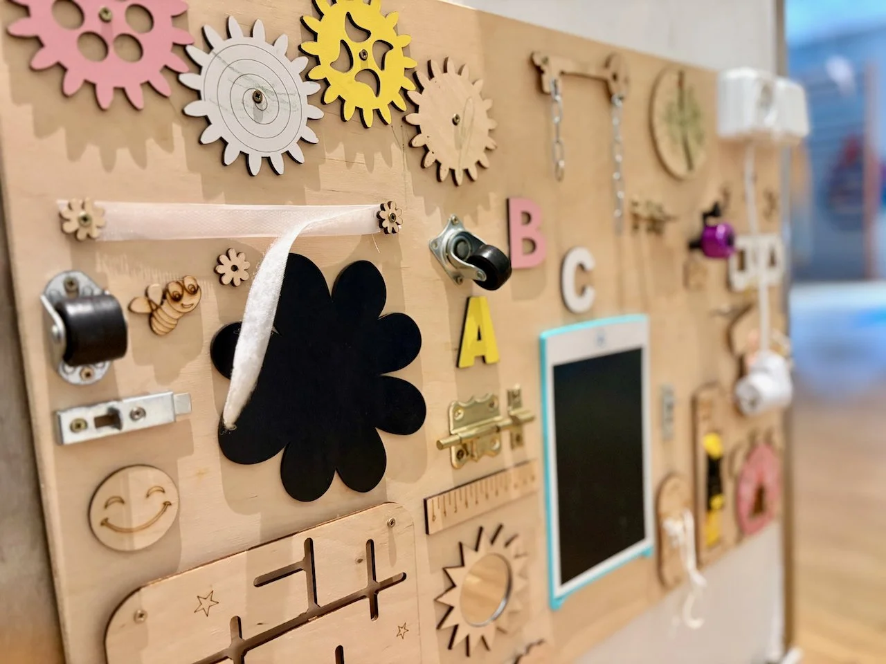 Foto Nahaufnahme von einem BusyBoard im Spielzimmer. Brett mit verschiedenen Spielzeugelementen wie Zahnräder und Klappen