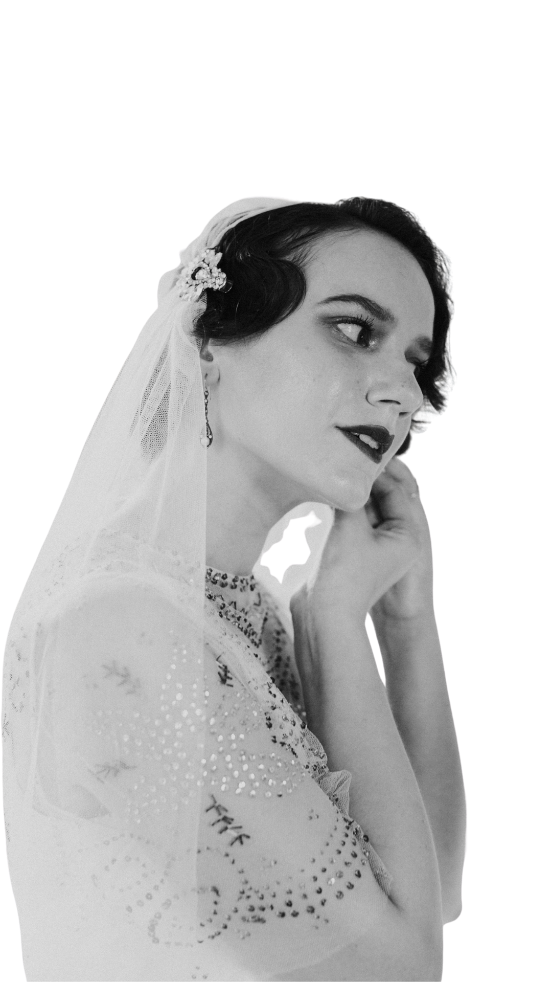 Une femme portant une robe de mariée et un voile, regardant de côté.