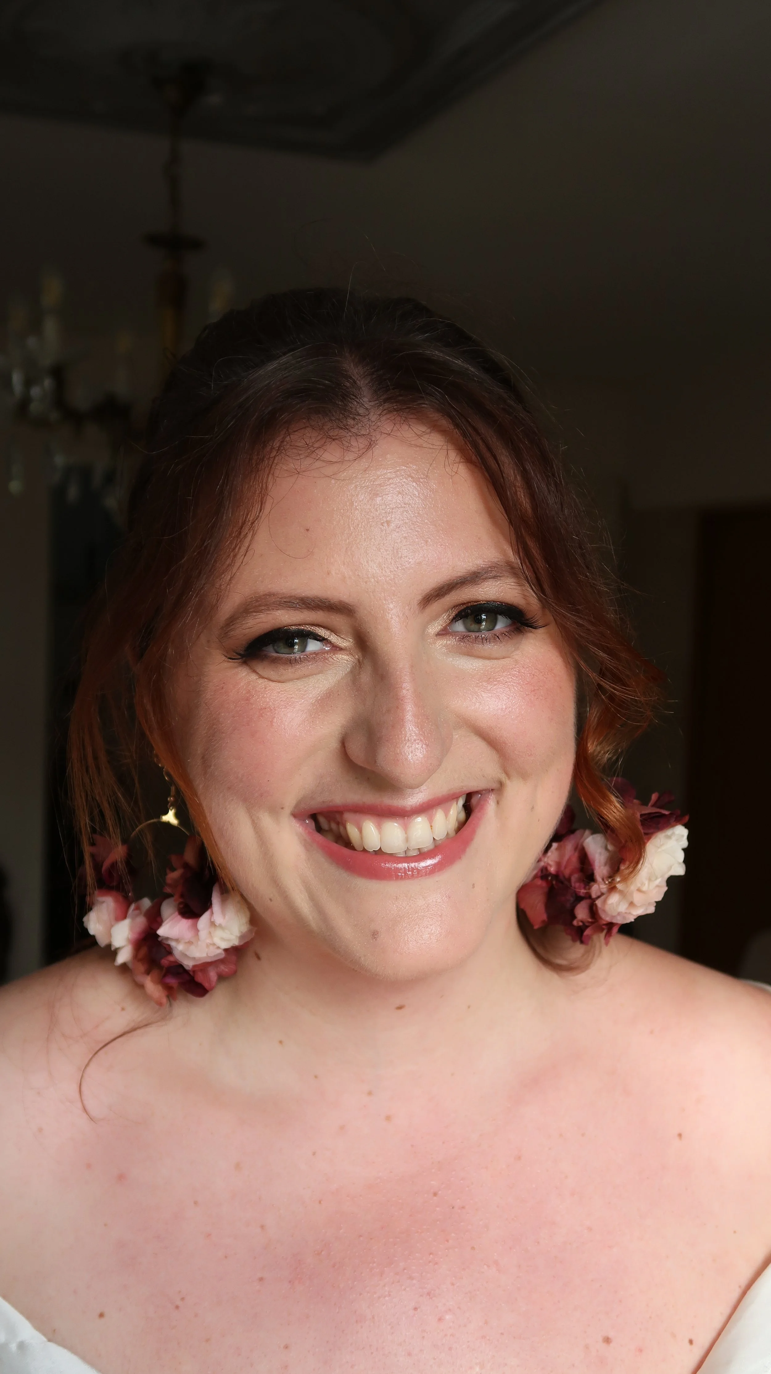 Un portrait d'une femme souriante avec des boucles d'oreilles en fleurs.