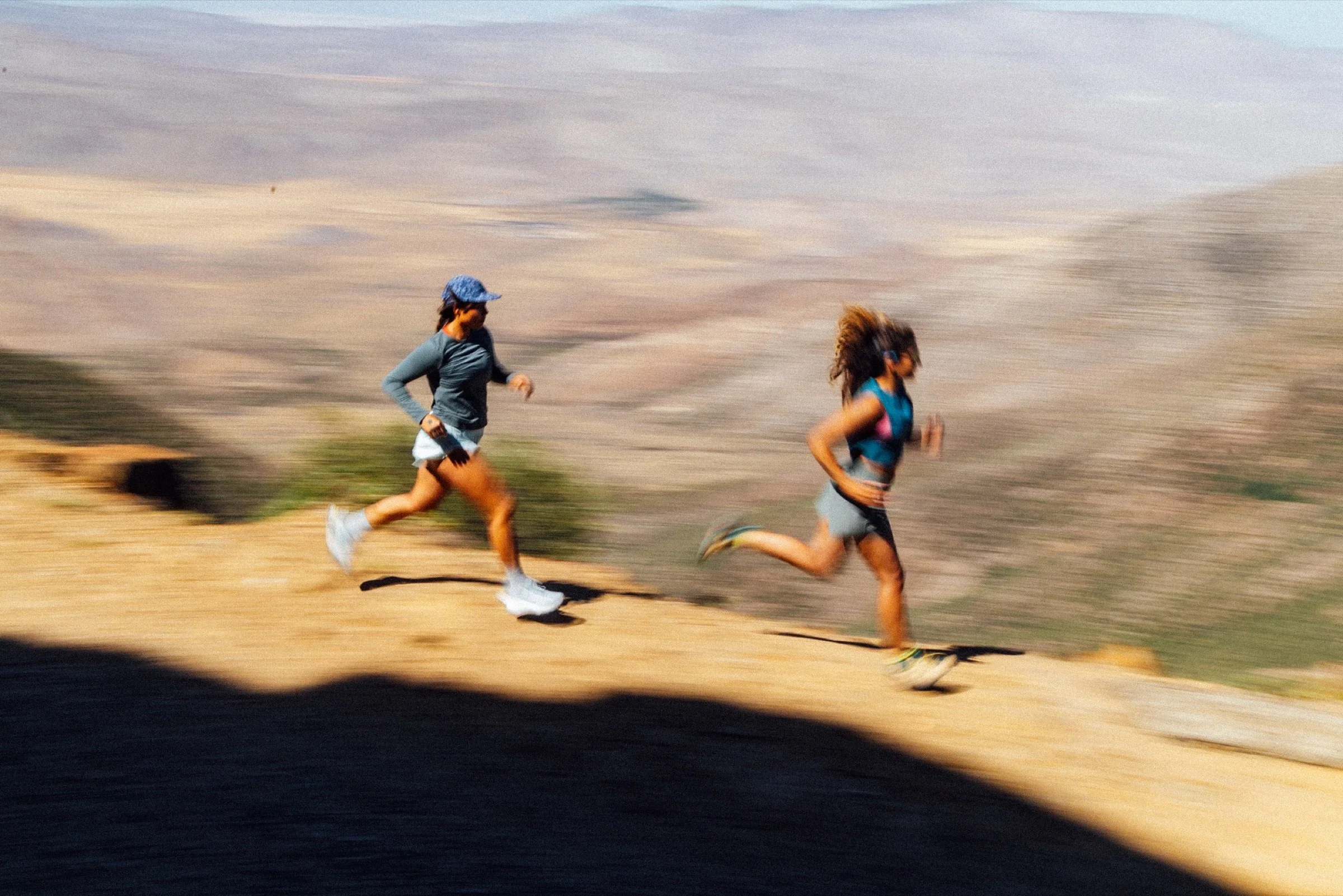 Two friends on a trail run along a mountain ridge