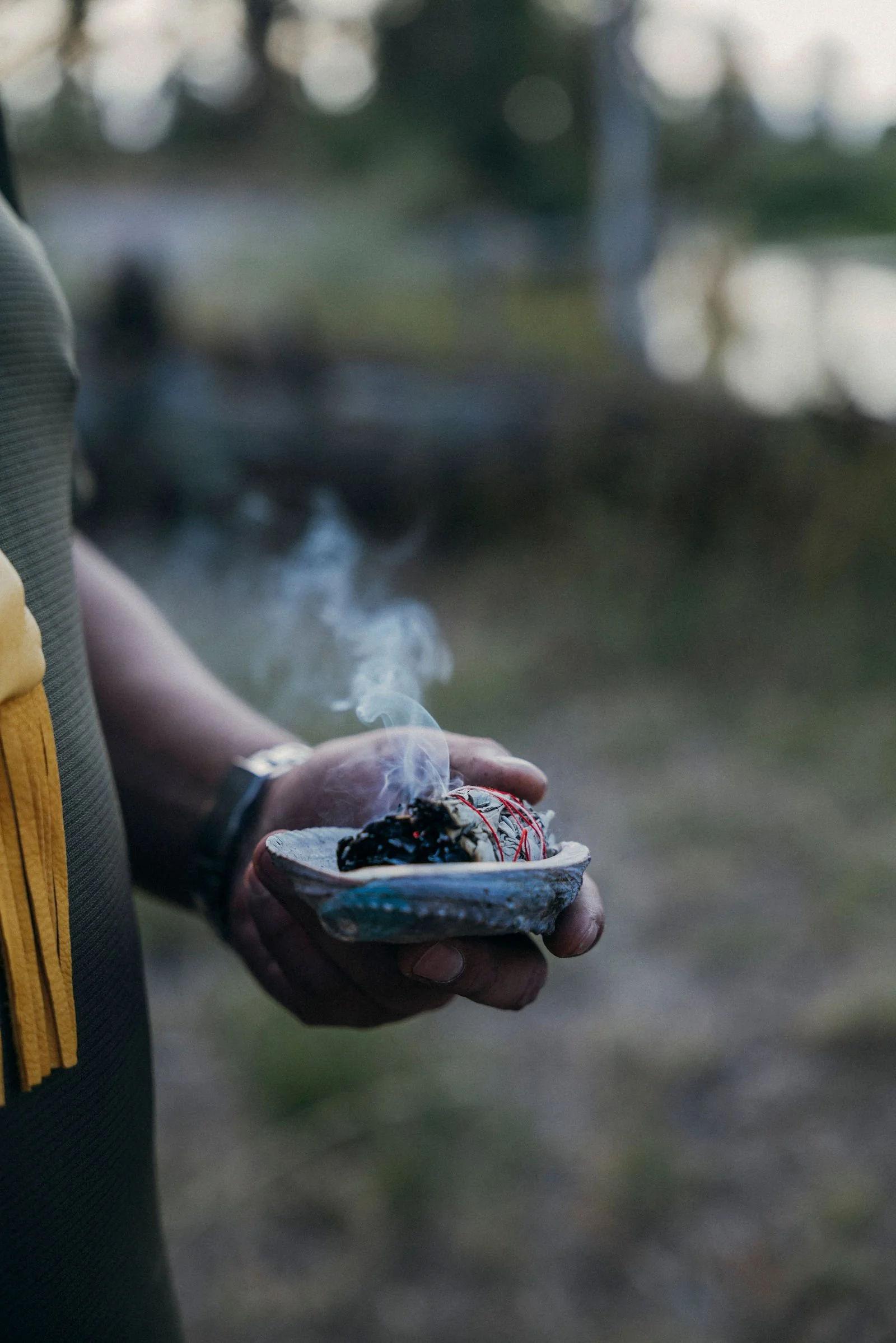 Hands holding a shell of smoking sage