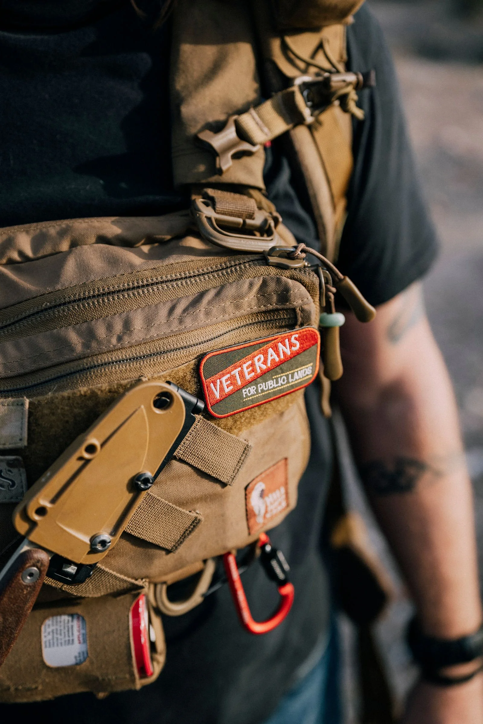 Close-up of a tactical chest rig with a knife and patches