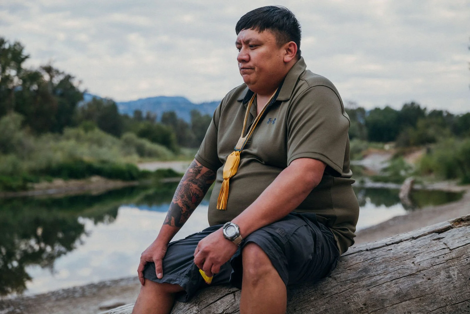Jonas sitting on a log beside a river