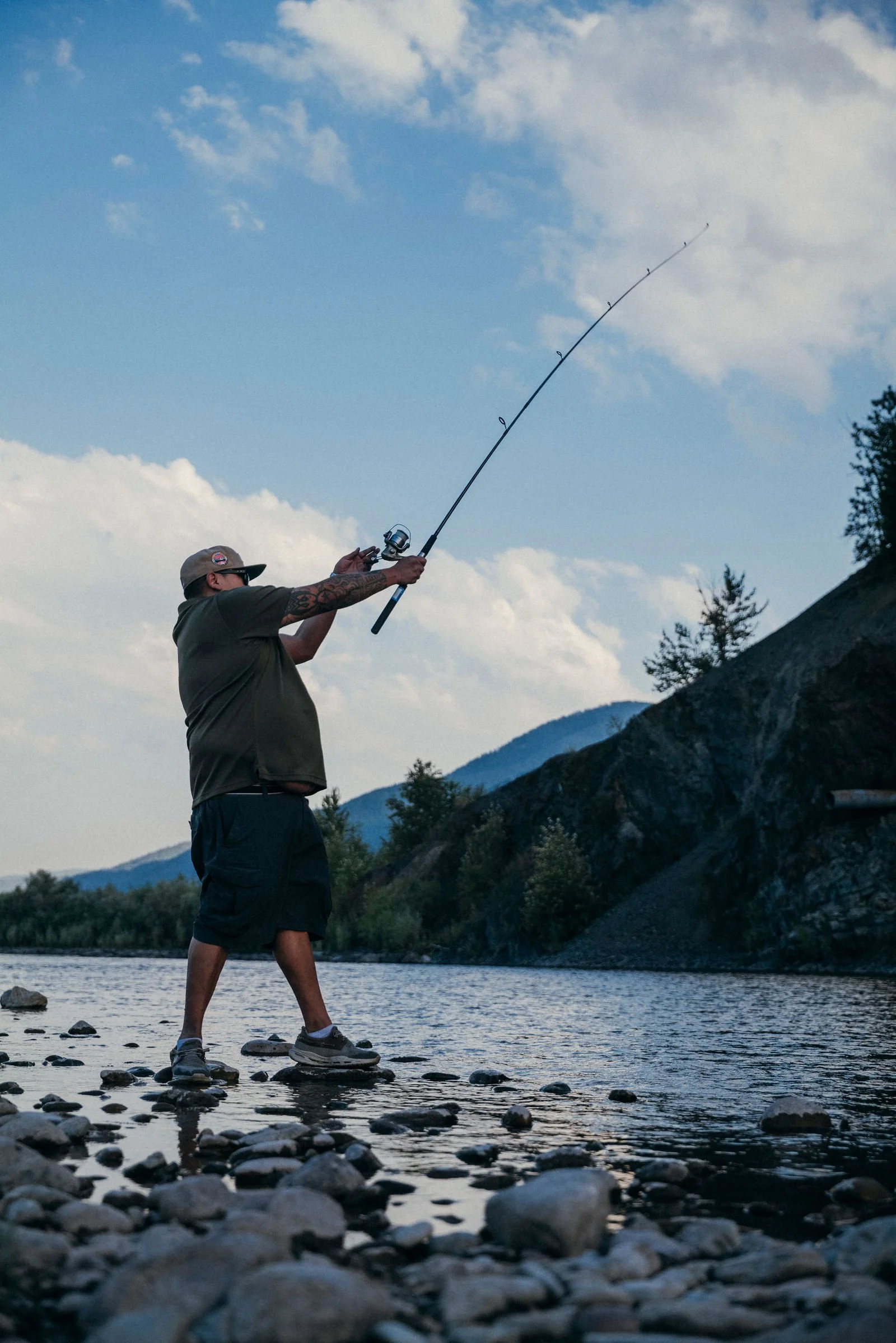 Jonas casting a fishing rod from a rocky riverbank