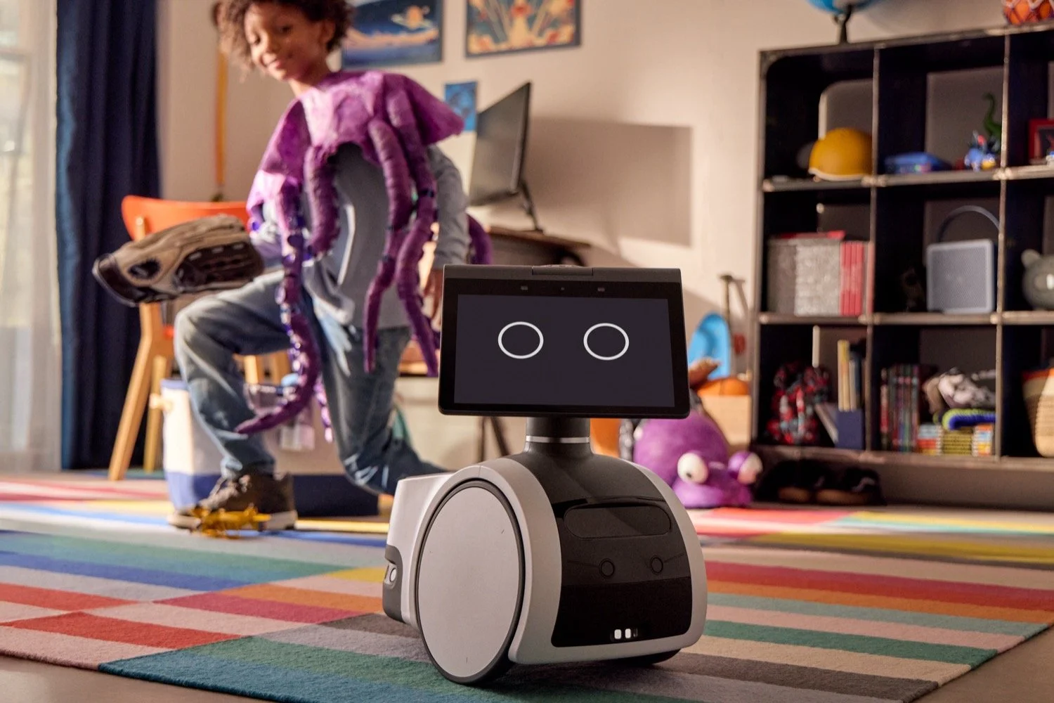 Boy in a purple costume dancing next to an Amazon Astro robot in a colorful kid's room