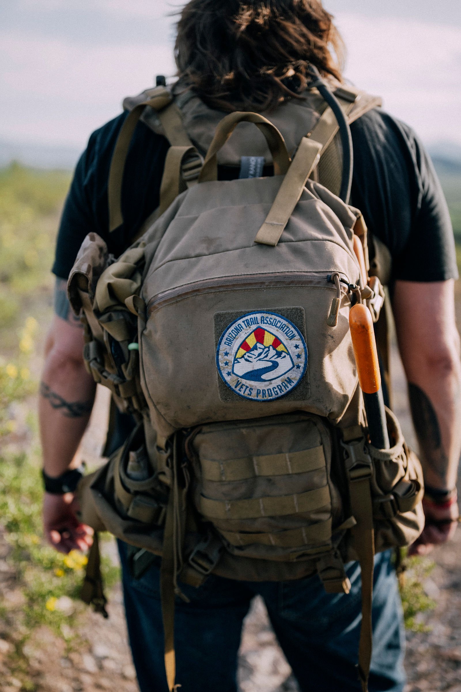 Chappy seen from behind wearing a patched backpack