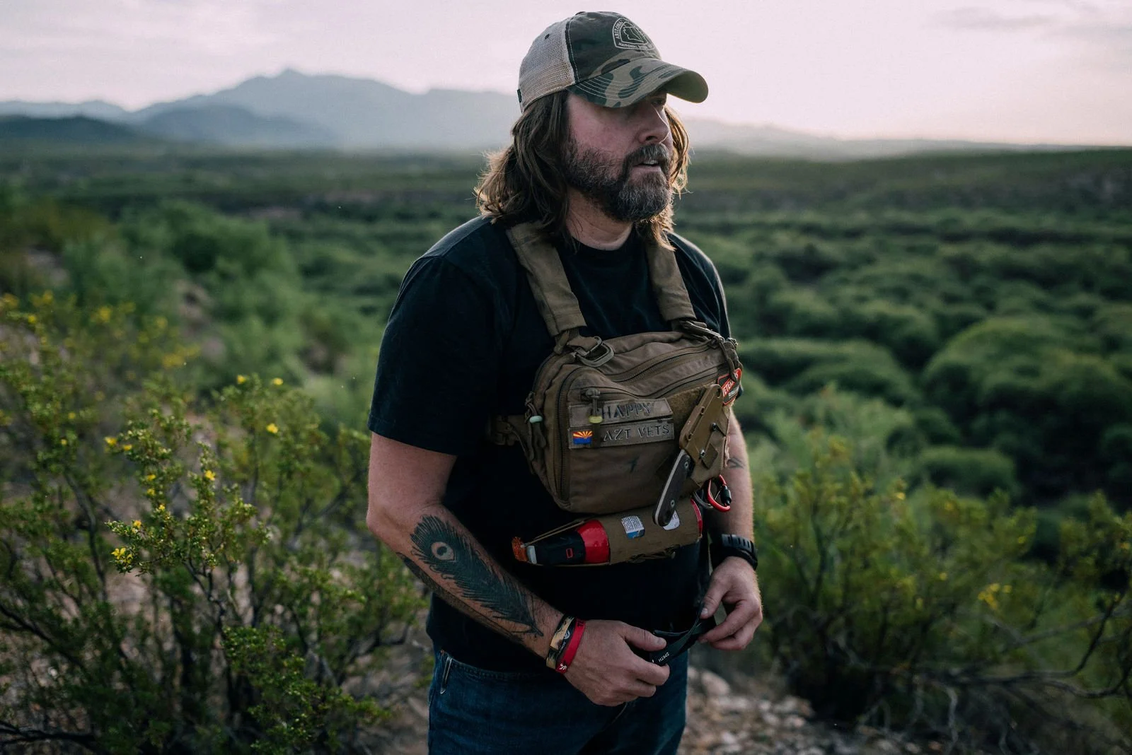 Chappy in a chest rig standing in desert brush