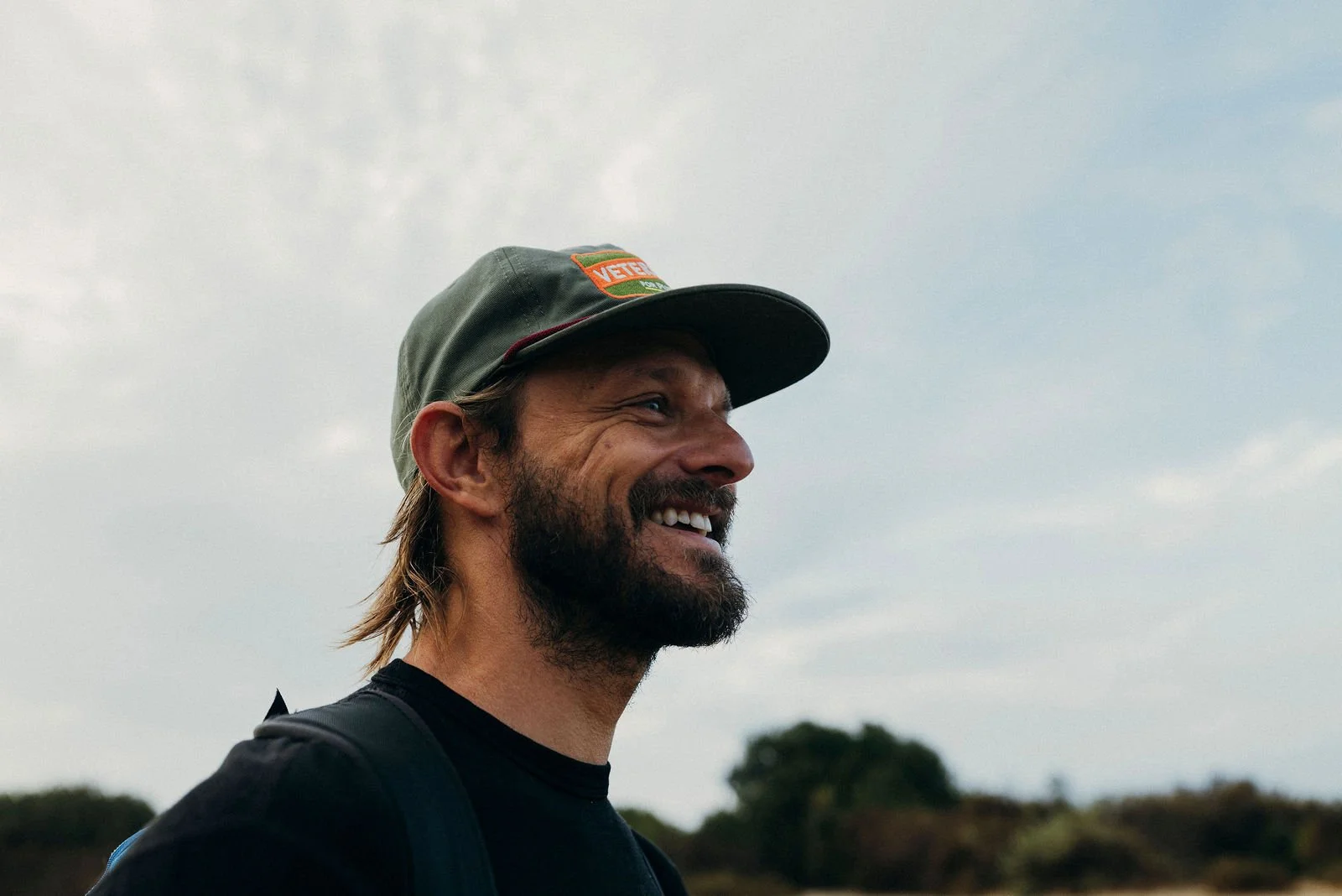 Nick smiling in a cap by the ocean