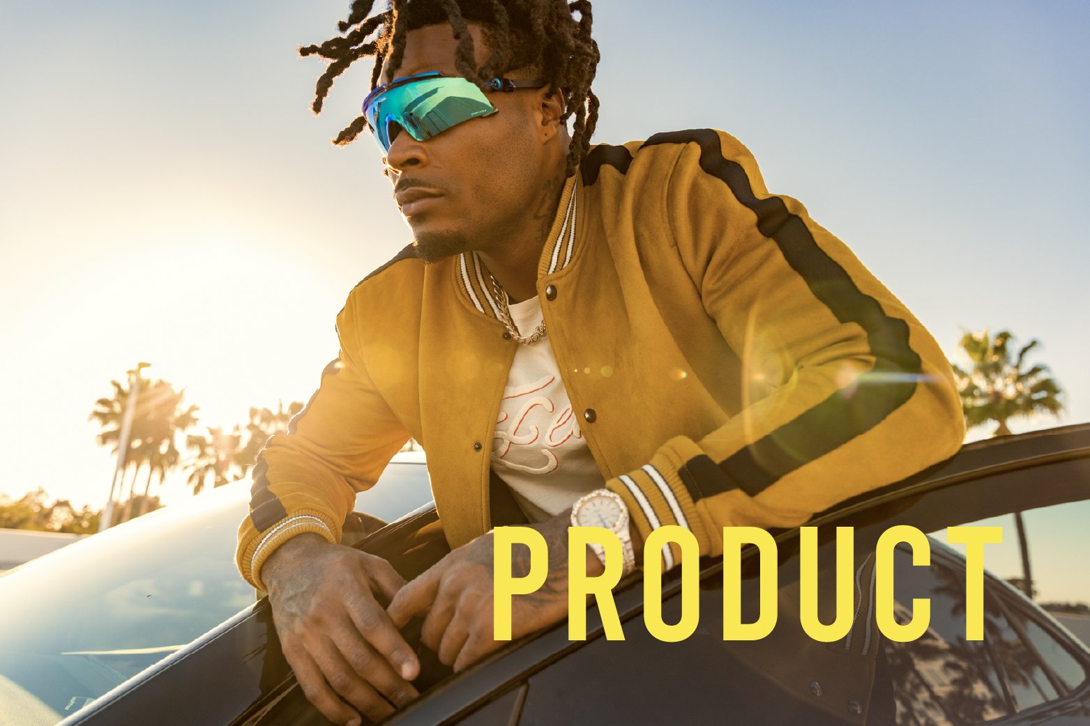 Product work: man in sport sunglasses and a yellow jacket leaning on a car at sunset