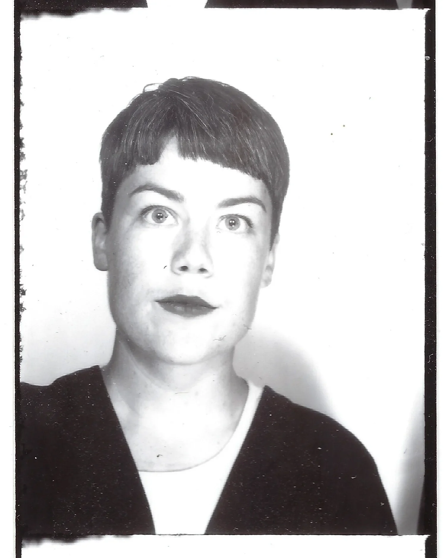 Black and white portrait of a woman with short dark hair, wearing a dark top with a light collar.