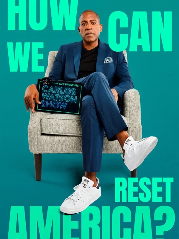 Man sitting on a gray armchair holding a sign that reads 'The Carlos Watson Show' with a teal background and large text that says 'How can we reset America?'.