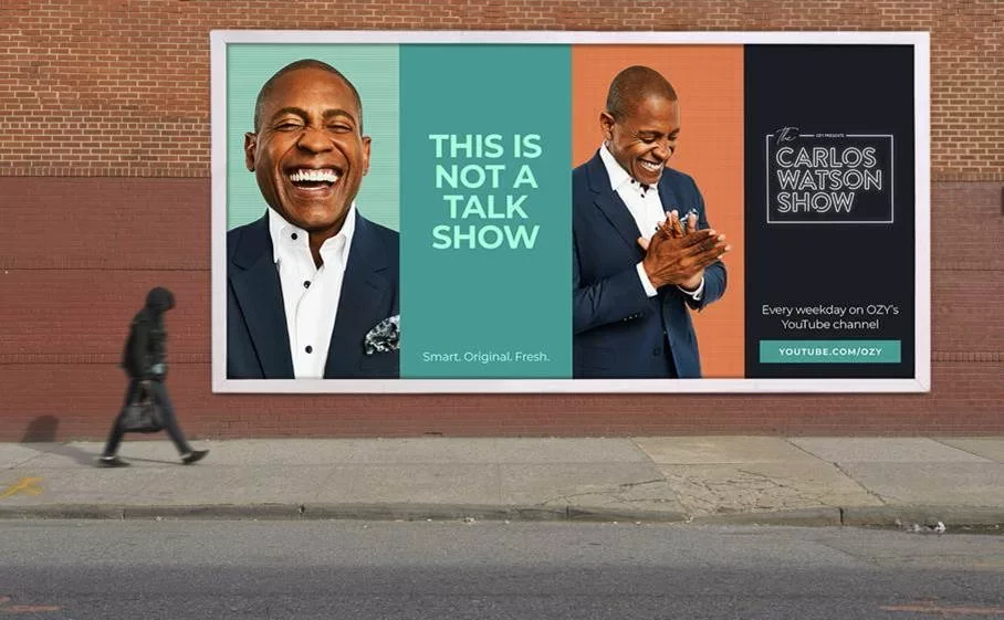 Billboard advertising The Carlos Watson Show, featuring a smiling man in a suit, with the message "This is not a talk show," and promoting Ozzy's YouTube channel.