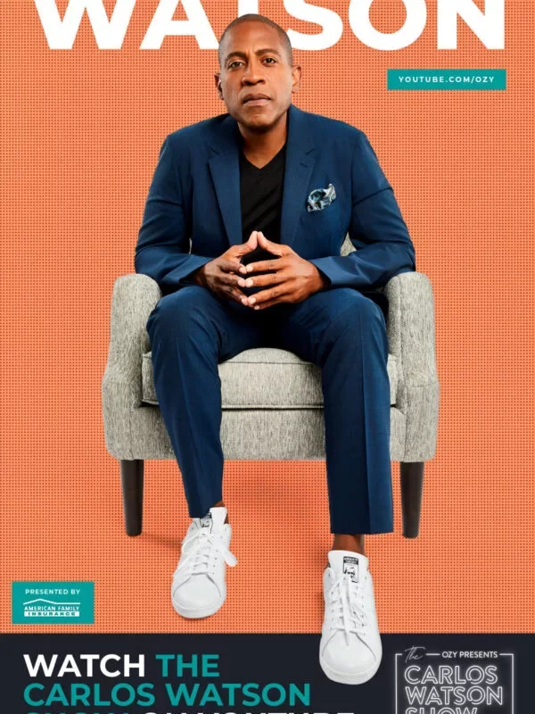 A man in a navy blue suit with a black shirt and white sneakers, sitting on a gray armchair against an orange background with large text reading 'WATSON' and a YouTube link, promoting a video featuring Carlos Watson.
