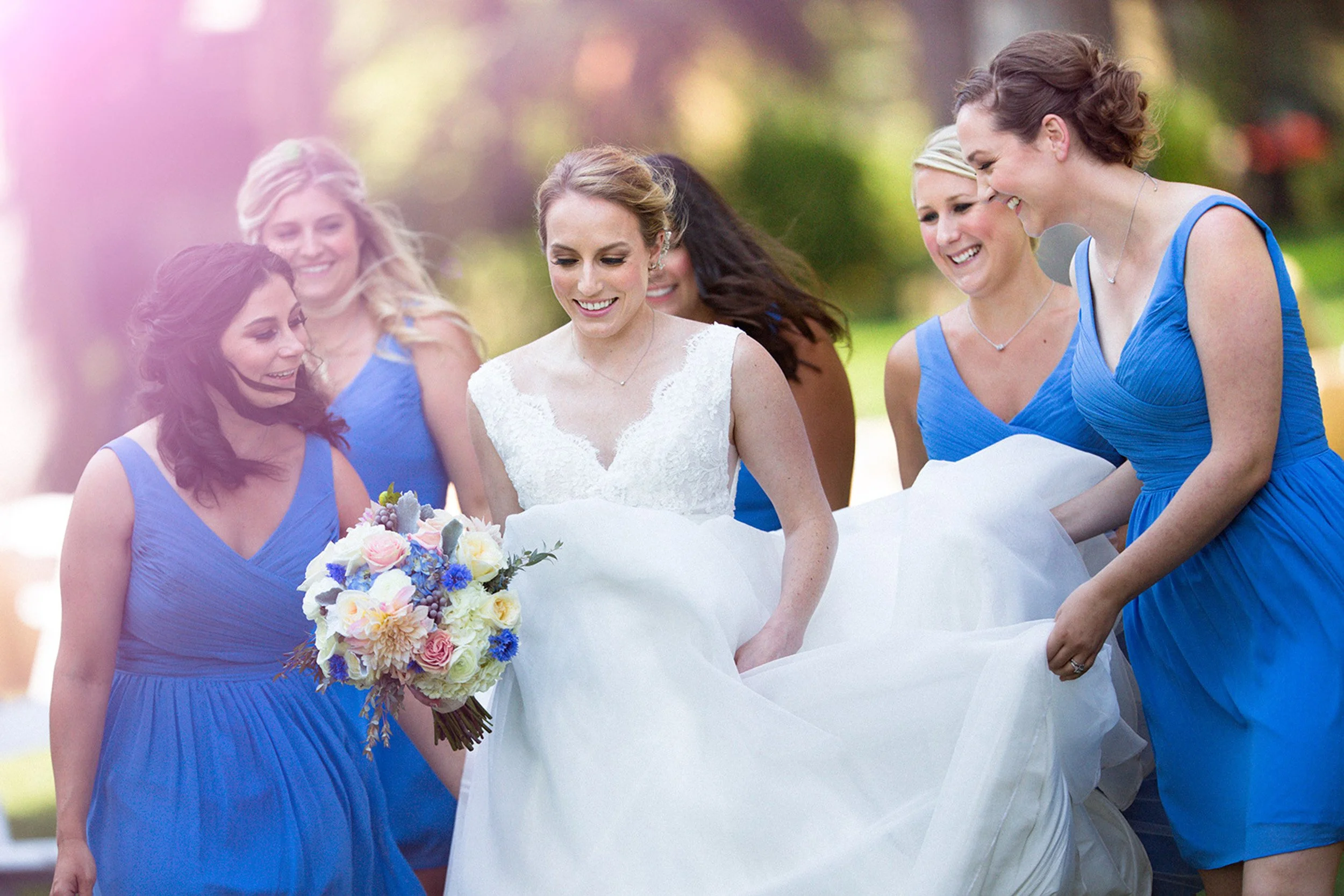 bride and bridesmaids holding wedding dress