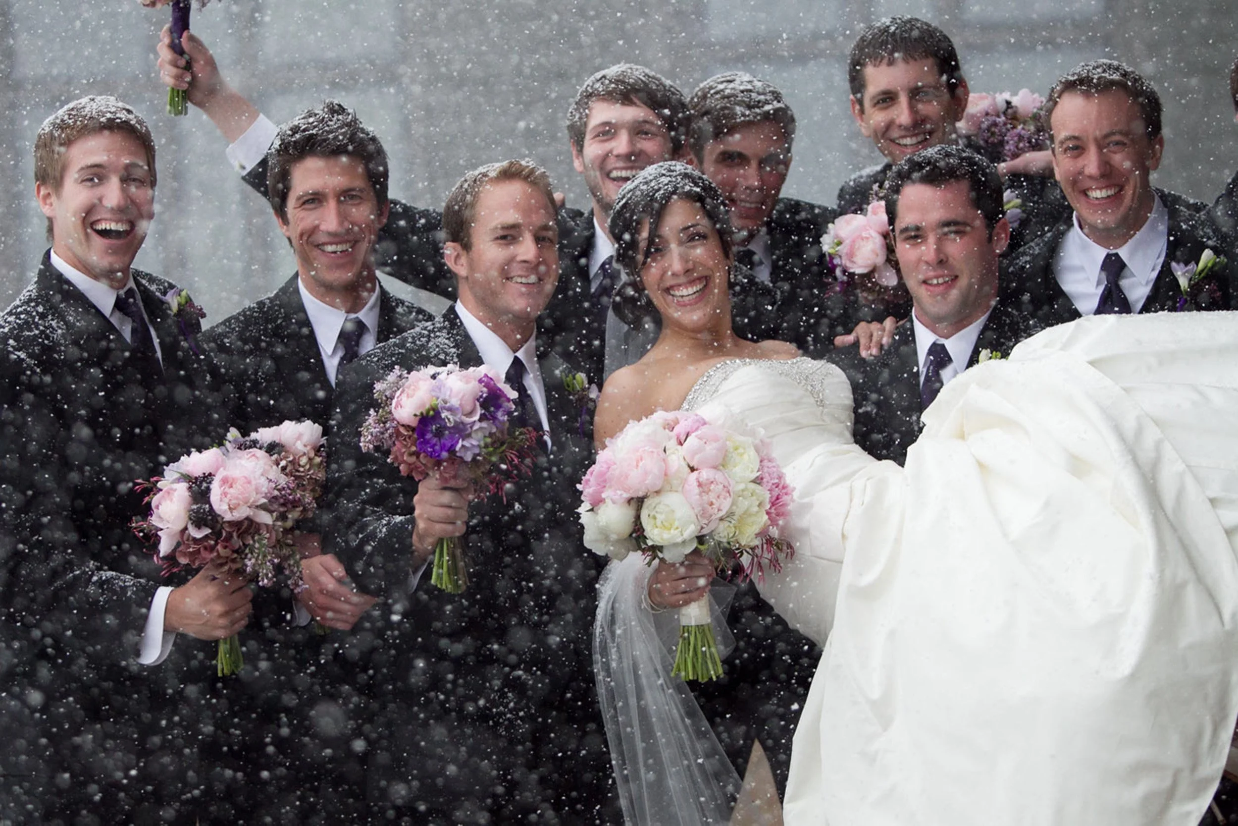 bride and groomsmen in falling snow