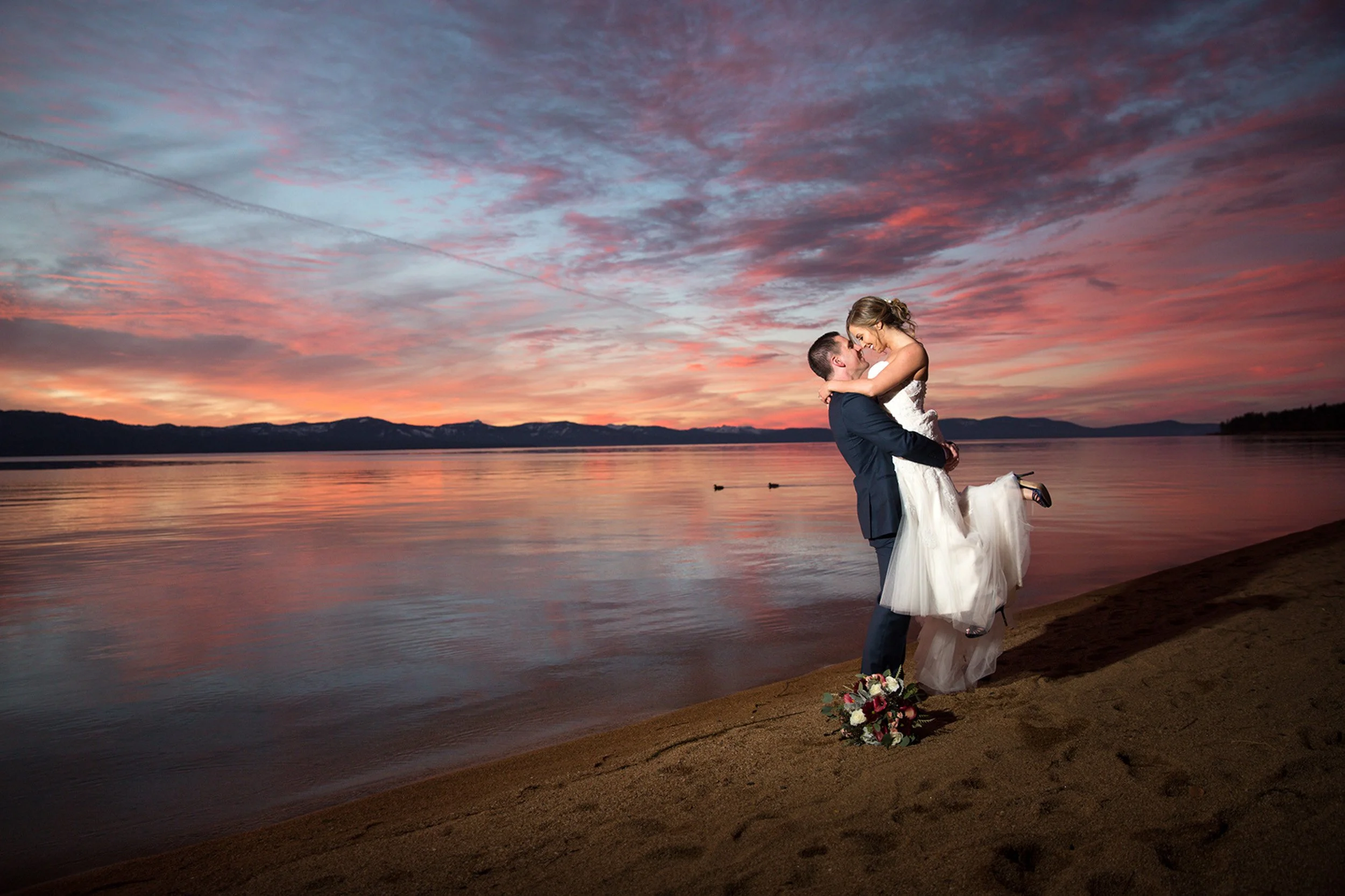 bide and groom embracing Tahoe shore