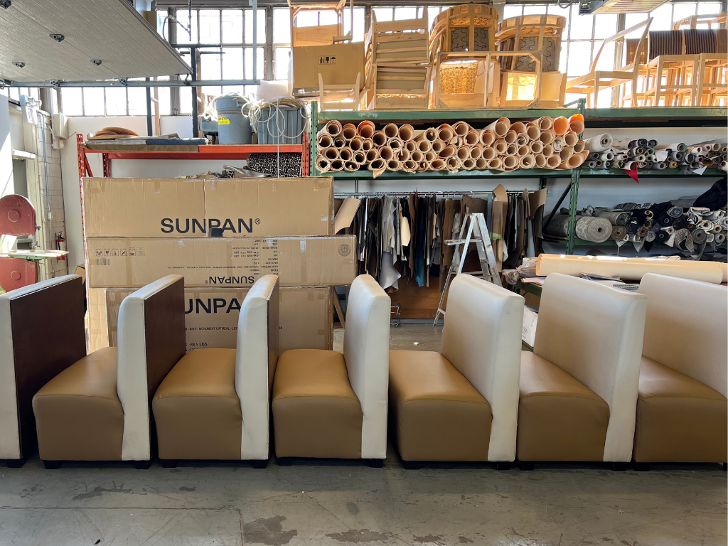 Six beige and white upholstered booth seats in a furniture warehouse.