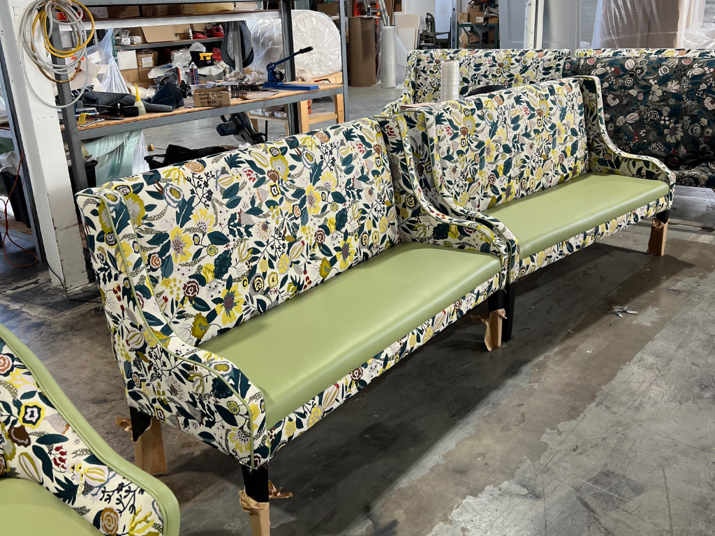 A vintage-style upholstered sofa with floral fabric and light green seat cushions in a workshop