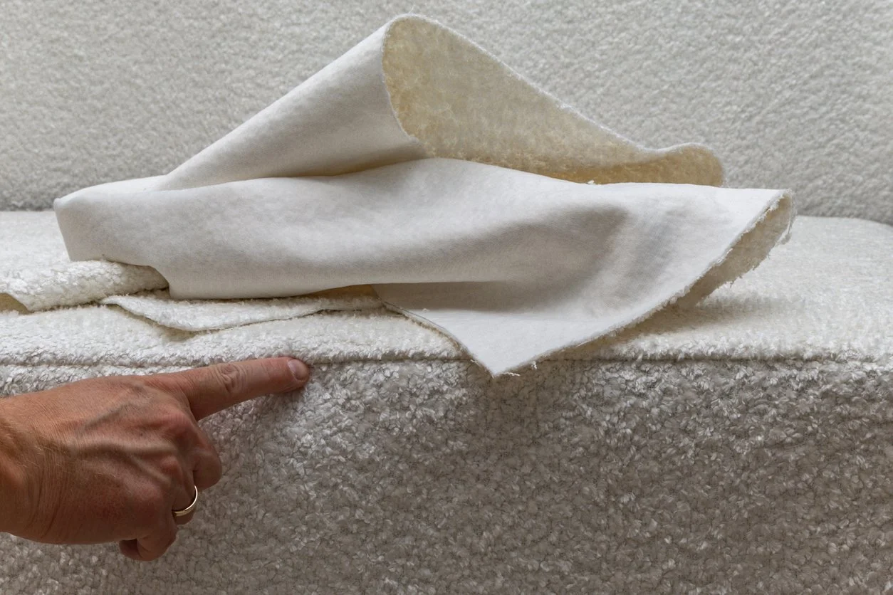 A person pointing at layered white fabric and batting material.