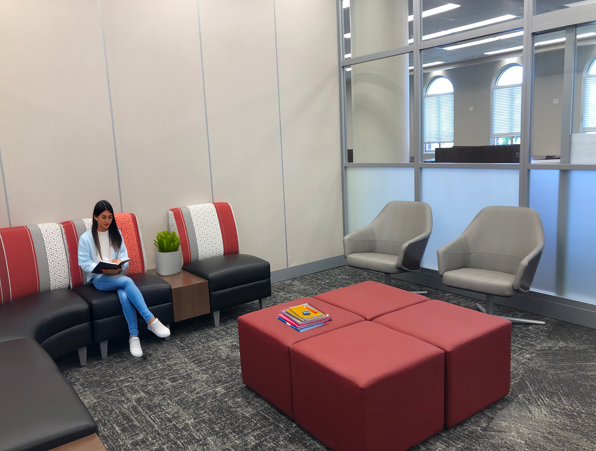 An upholstered circular seating area and red square ottomans  with fretted glass wall to let light in. project by B Group Architecture, Inc