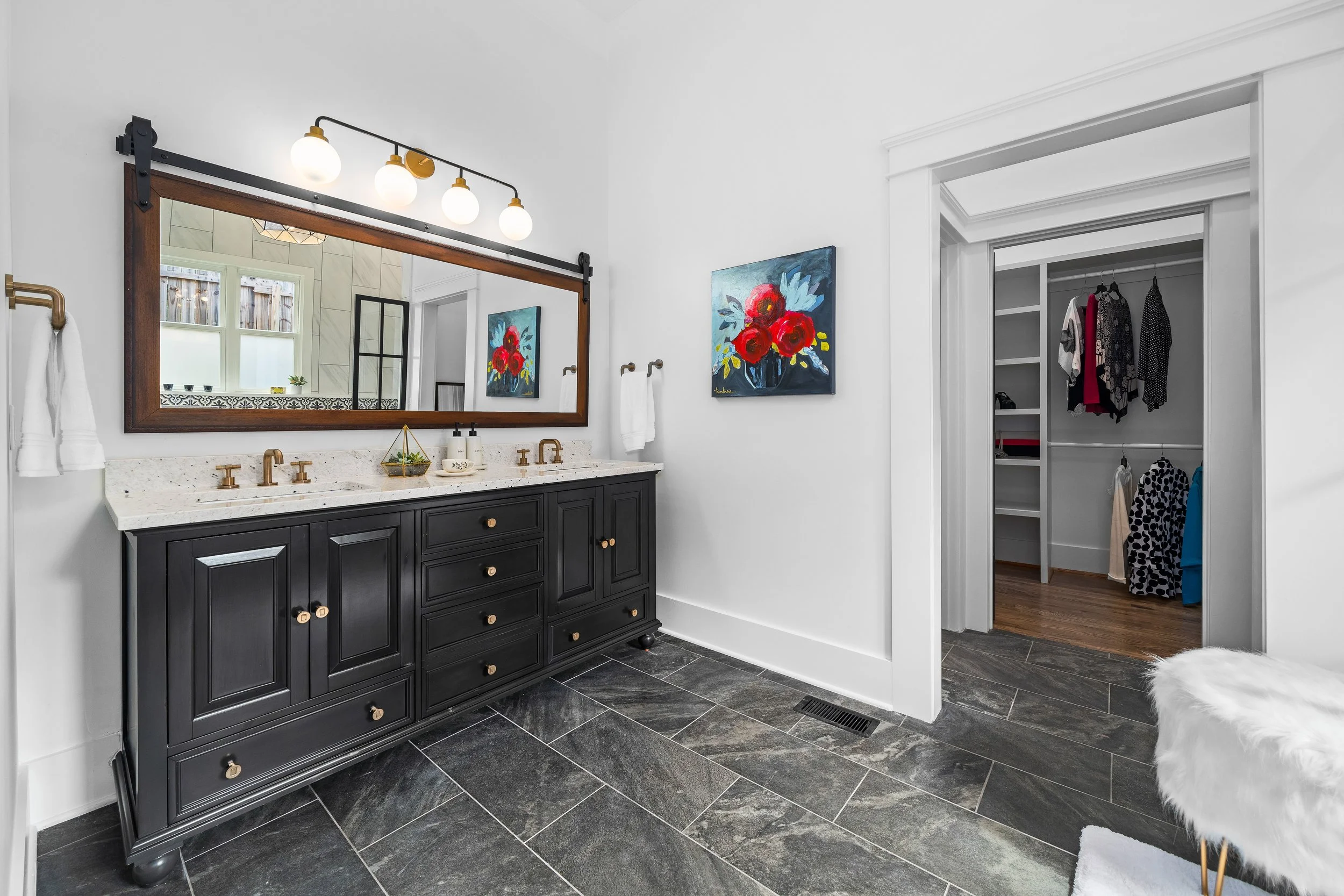 A view of a renovated master modern bathroom with a black vanity, granite countertop, large mirror, and a contemporary light fixture. project by B Group Architecture, Inc.