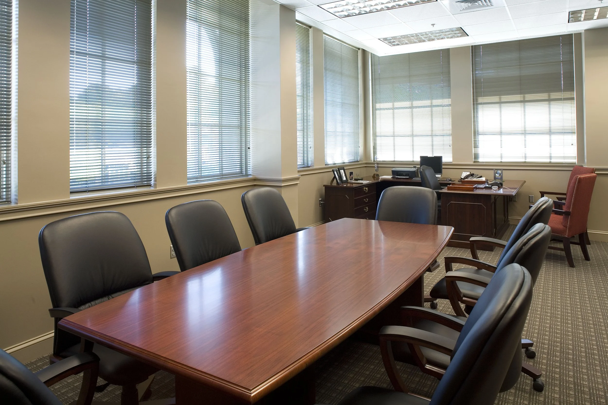Conference room with a large wooden table, black leather chairs. The room is flooded by natural light and highlighted with a chair rail  project by B Group Architecture, Inc.